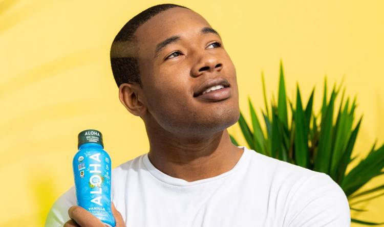 a man is holding a bottle of aloha vanilla tea