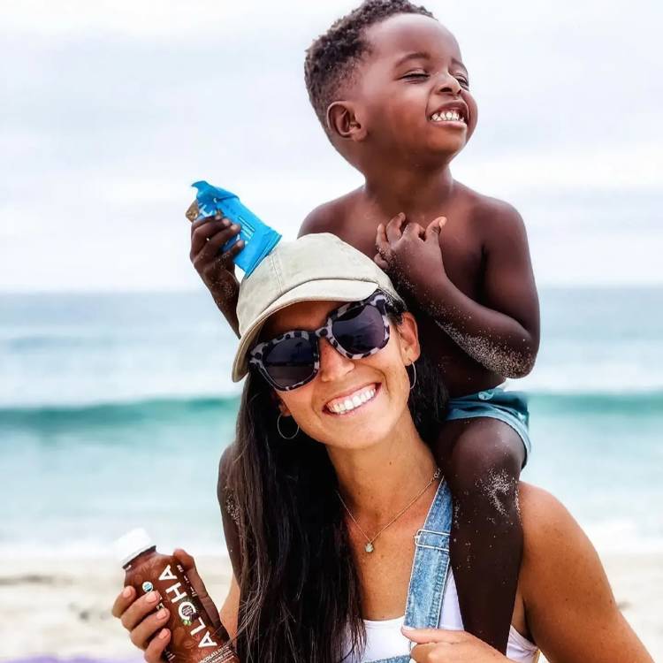 a woman is carrying a little boy on her shoulders on the beach