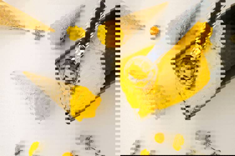 a scoop of yellow ice cream is being scooped out of a pan