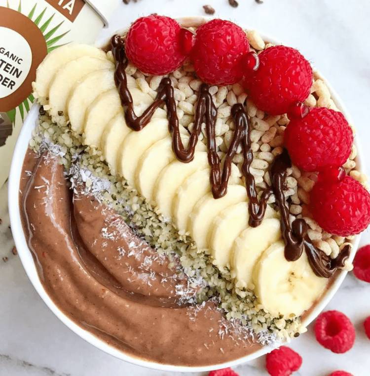 a bowl of chocolate smoothie with bananas and raspberries on top